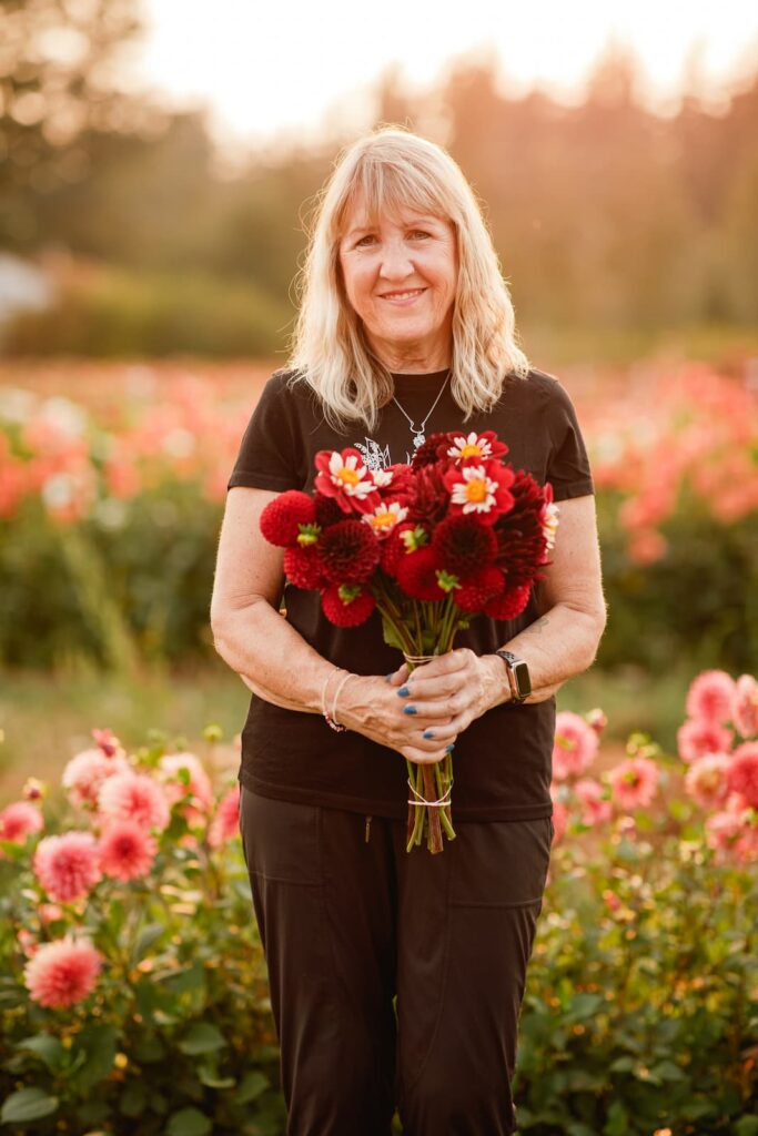 Lee Pusch standing in a dahlia field at sunset. Photo courtesy of Triple Wren Farms.